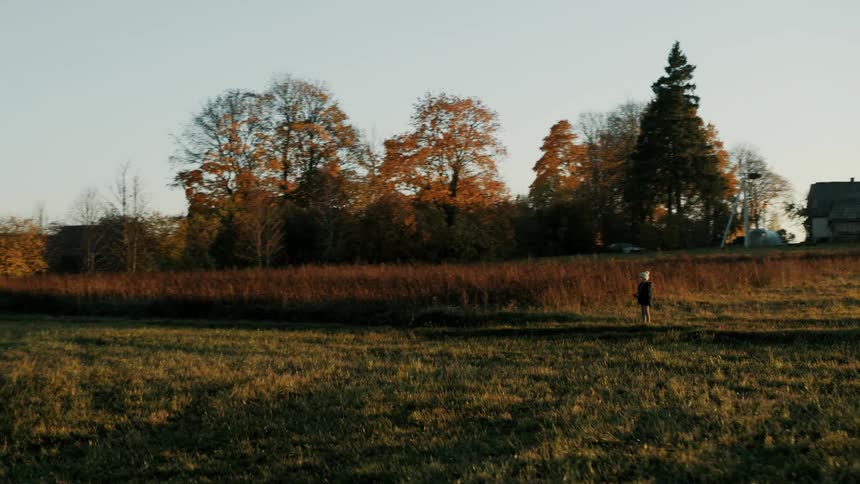 A person controls a drone in a large open rural field