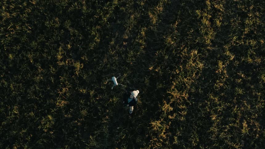 A child flies a drone in a field during the day