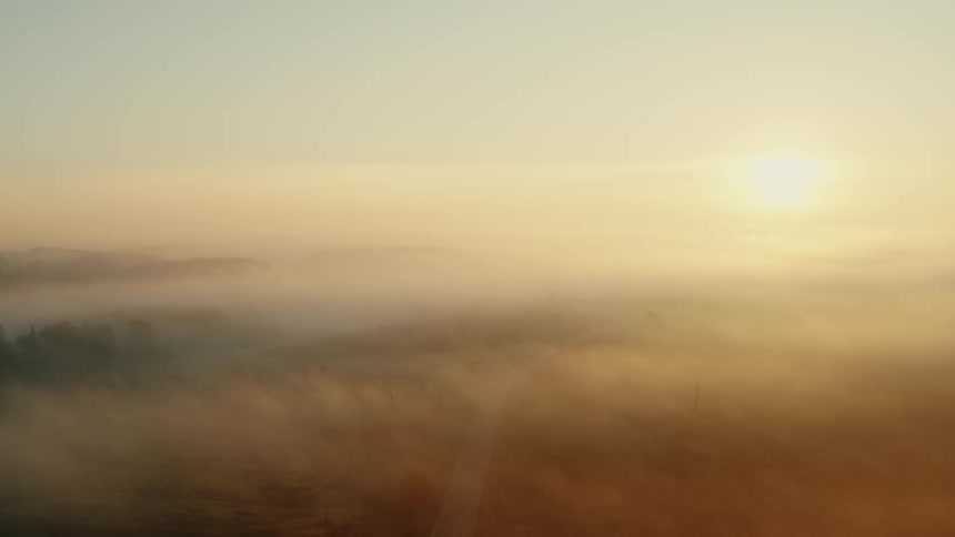 Sunlight shining down on a foggy area that has a long road and land