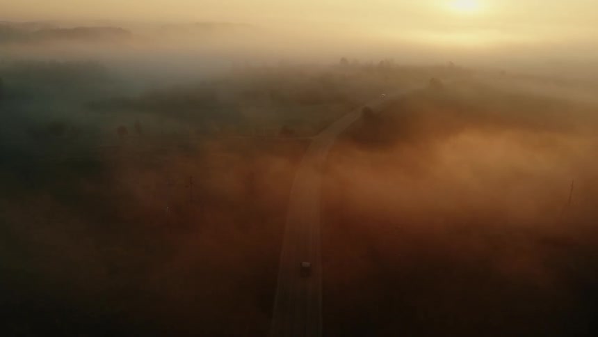 A car drives down the foggy road