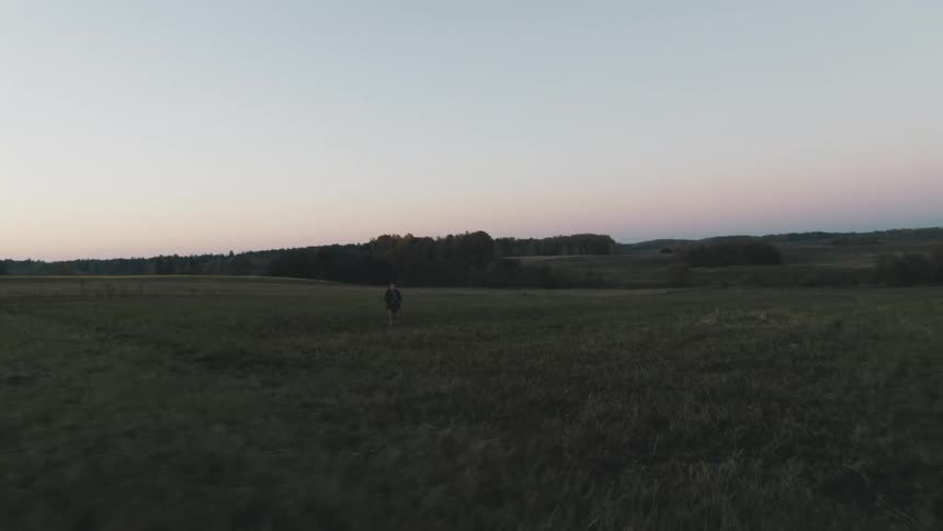 A boy stands in an open field in a thick coat and hat