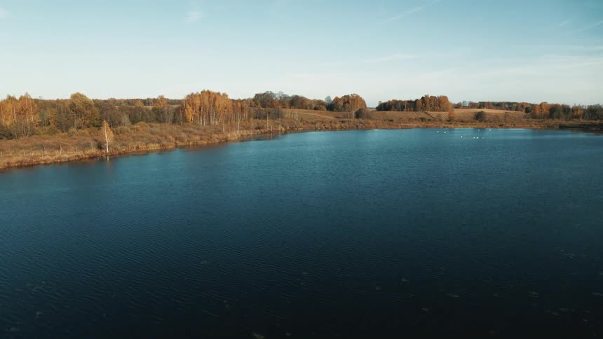 A lake surrounded by hilly grassland in the countryside on a clear day