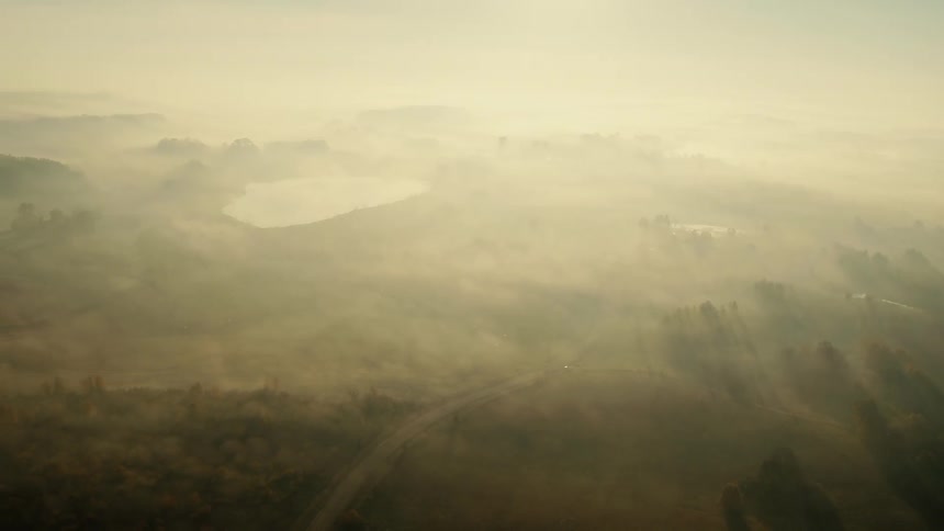 A landscape with trees hills and a road with the sky and clouds in the background