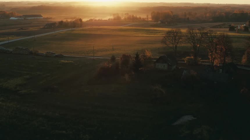 Aerial view ofa green countryside with houses at sunset