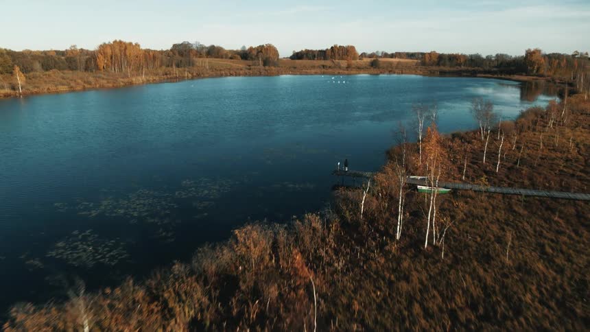 Aerial footage of a dock extending out towards a large lake at daytime