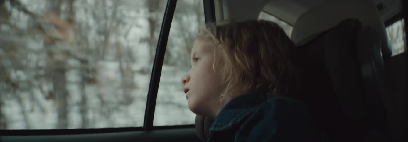 A child is looking out the car window as it travels