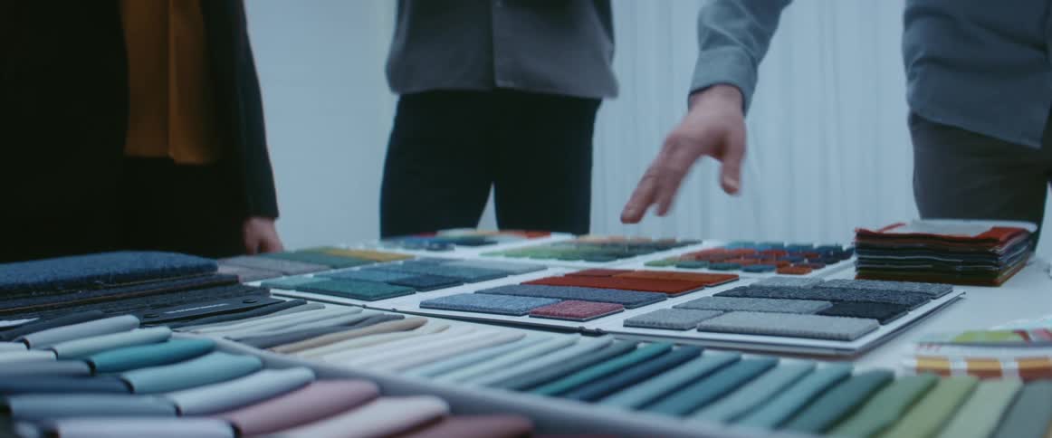 Three people in a room at a table full of material swatches
