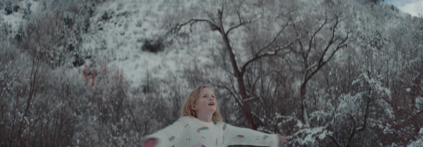 Girl wearing pajamas spinning outdoors on a snowy day