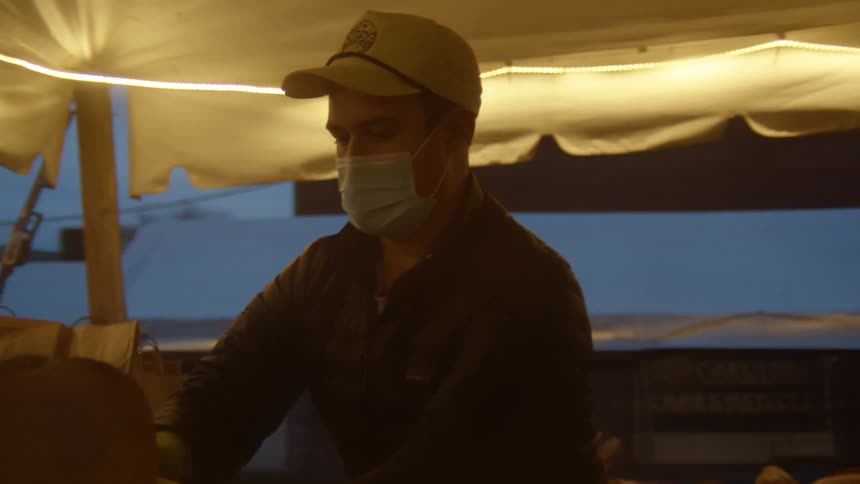 A man with a hat a mask and gloves putting bread in a basket