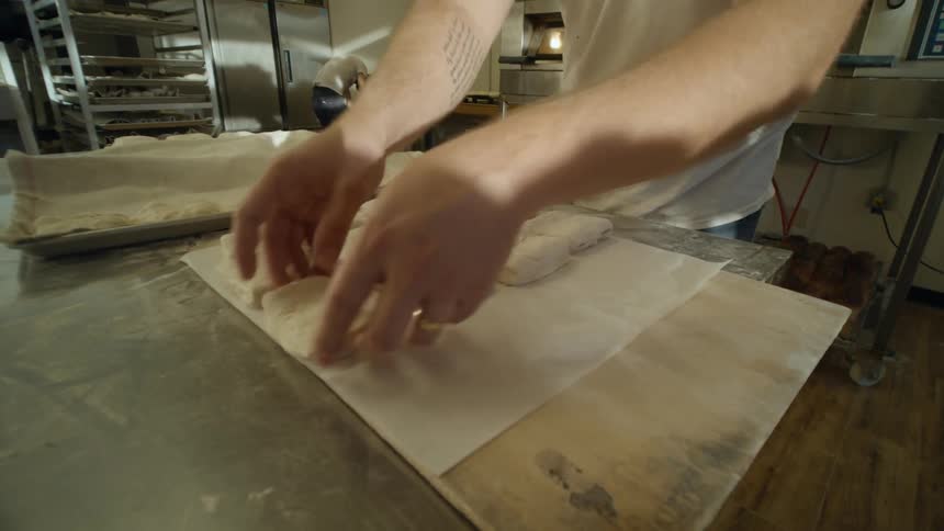 A man with a hat in a kitchen preparing pastries with an oven in the background