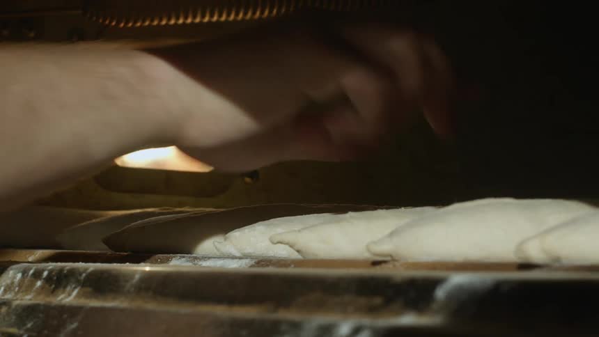 A person baking bread in an oven