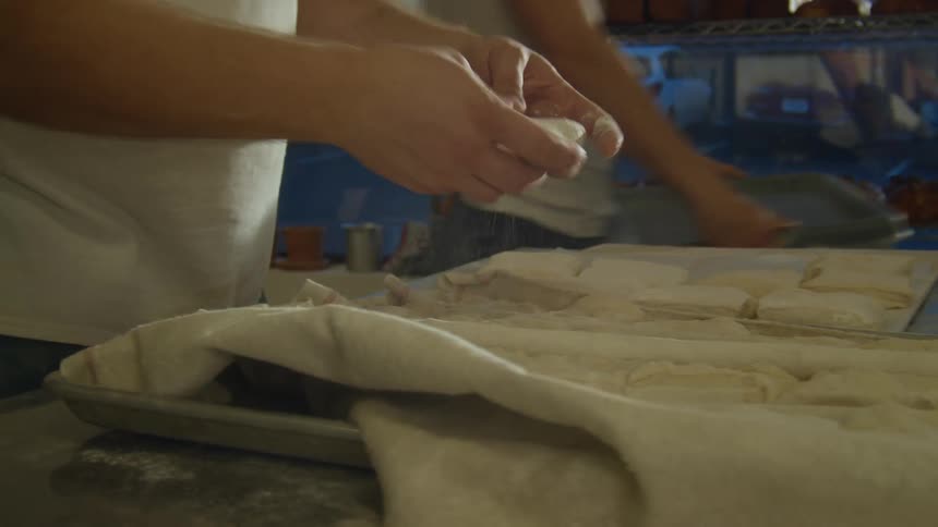 A kitchen employee moves pastries from one to another
