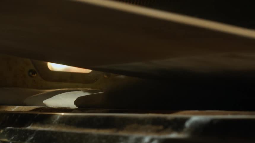 A baker uses a peel to place bread dough inside the oven