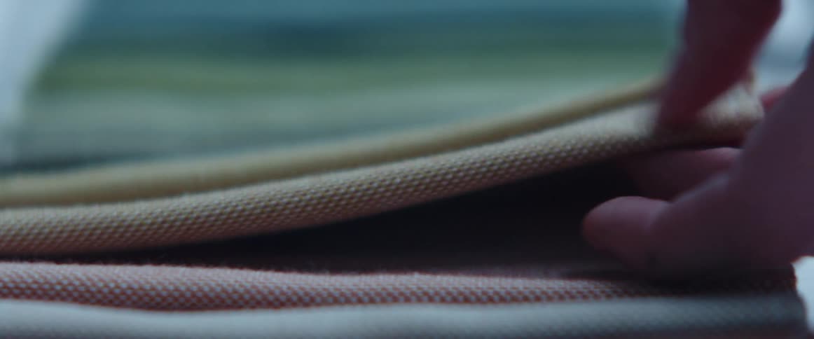 A person touching different fabrics on a table