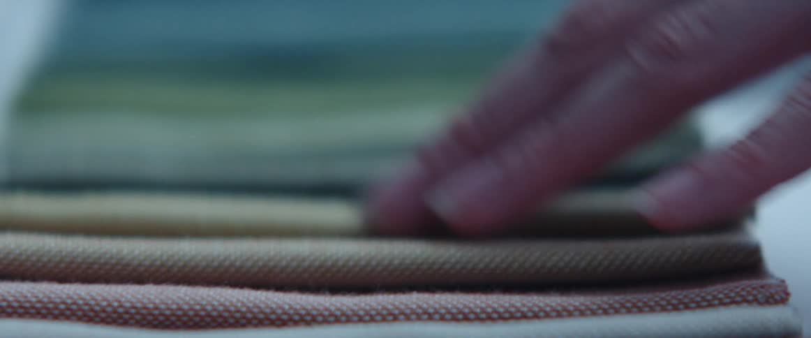 Person feels and strokes fabric laid out in overlapping row