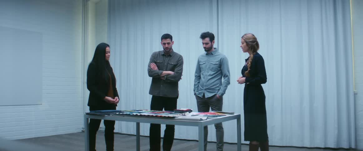 A woman discusses fabric samples laid out on a table with clients