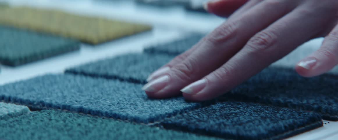 A person touching different fabrics on a table