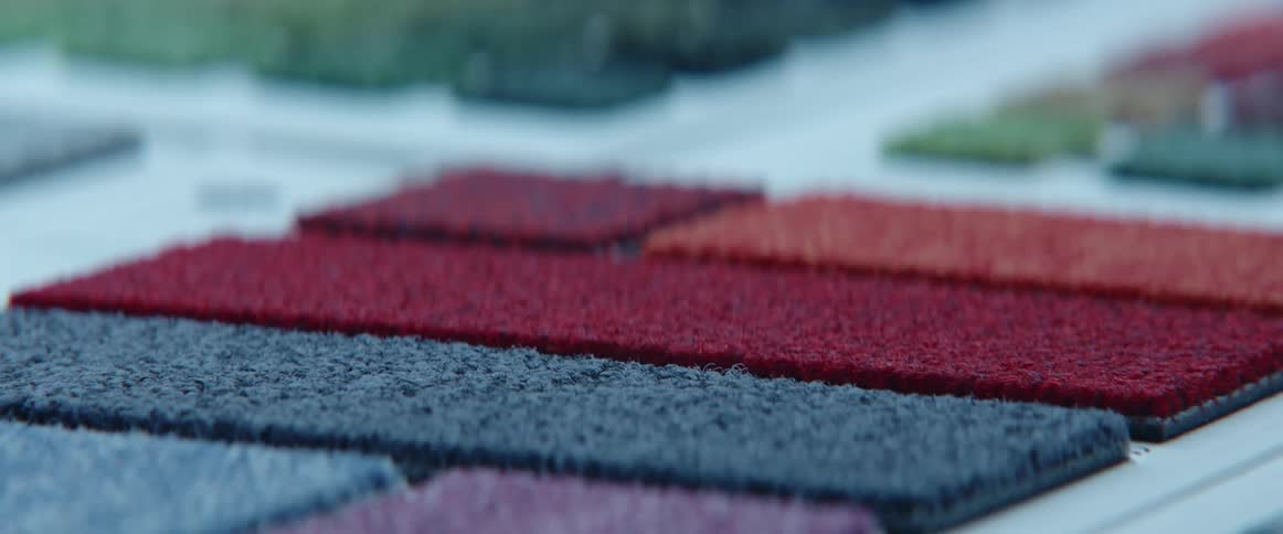 A person rubs carpet samples lying atop a table with their fingers