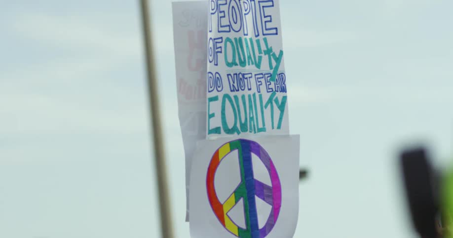 A policeman walking around a group of protesters holding signs