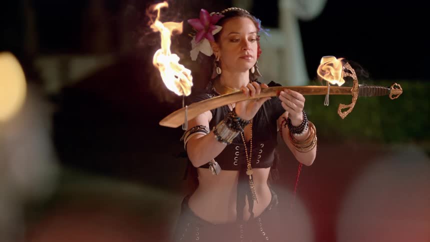 A woman dancing with a sword on fire