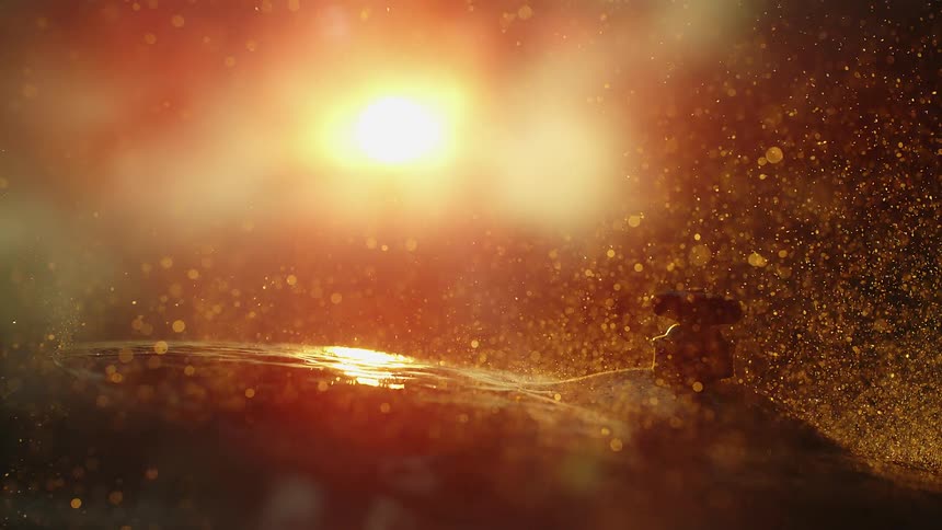 A drum stick hitting a cymbal with water on the cymbal splashing