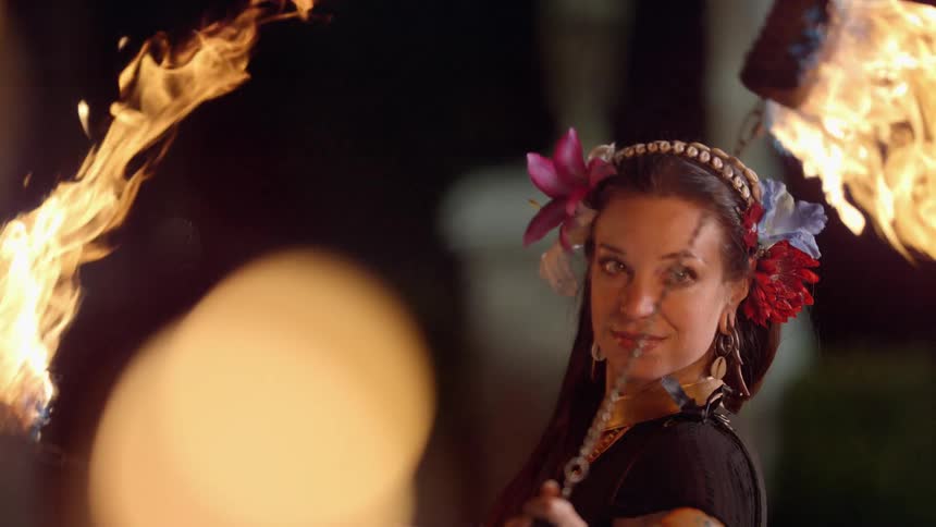 A woman with flowers in her hair dancing with fire and heat