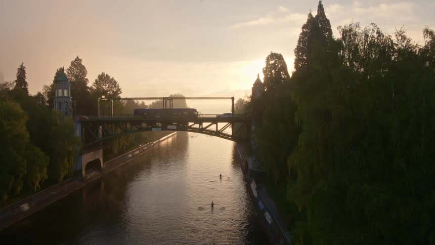 Rowers glide along the water as morning commuters travel overhead along the Montlake Bridge at sunrise