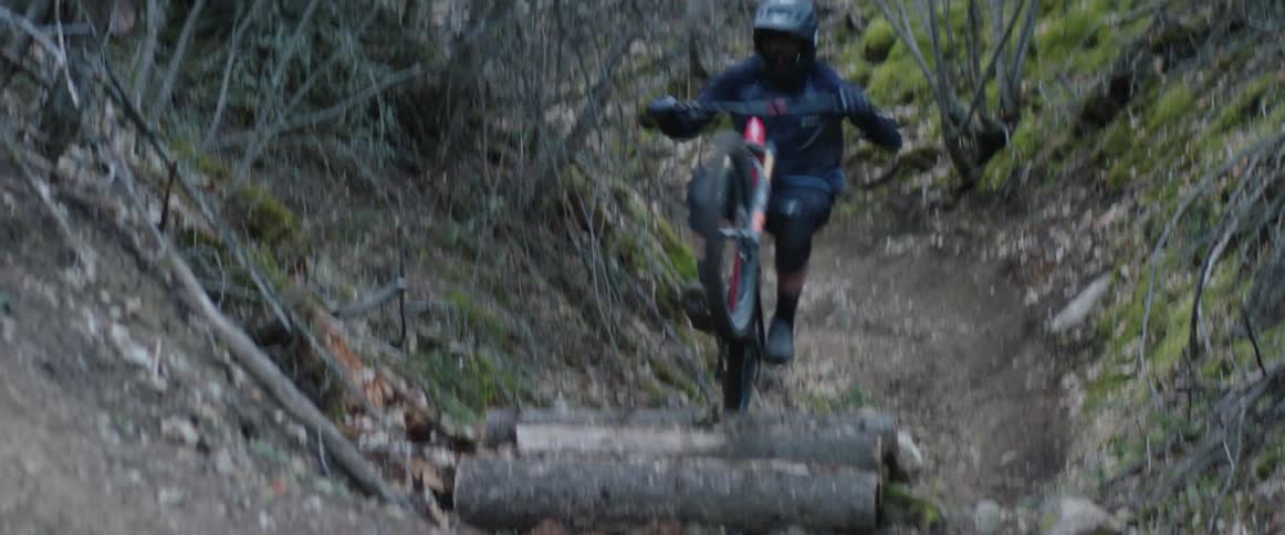 A person riding a mountain bike hits jumps and quickly corners down the trail