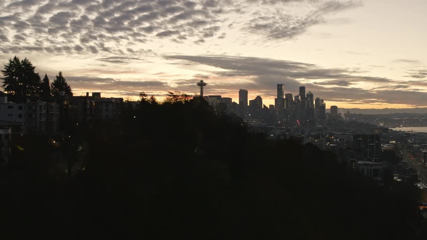 Skimming the tree line of Queen Anne hill as the morning commute starts in downtown Seattle under a beautiful sky