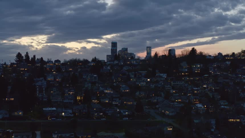 Ascending above lakefront homes in the Central District toward downtown Seattle as the sun sets behind beautiful clouds