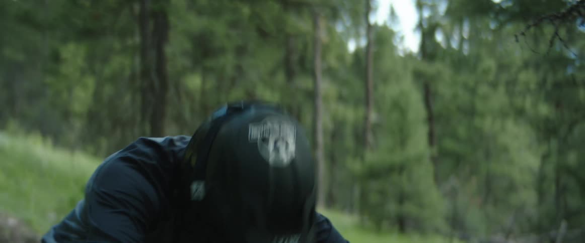 A male mountain cyclist in a forest drops into bike trail