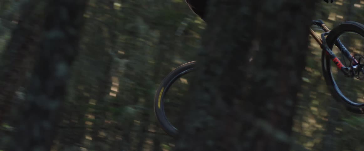 A man jumping his mountain bike through the air on forest trail