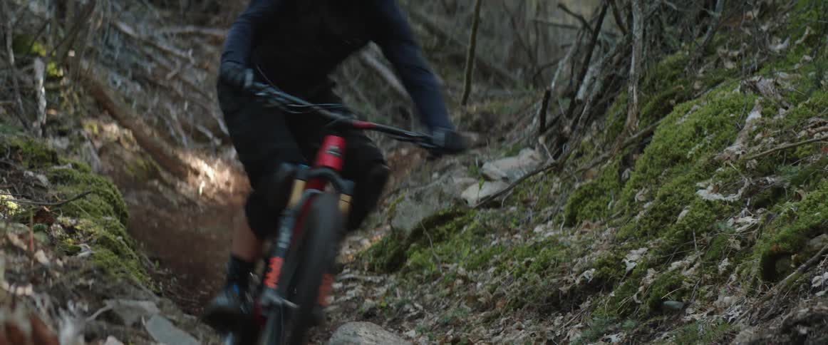 A person riding a mountain bike down a trail and hits dirt corner