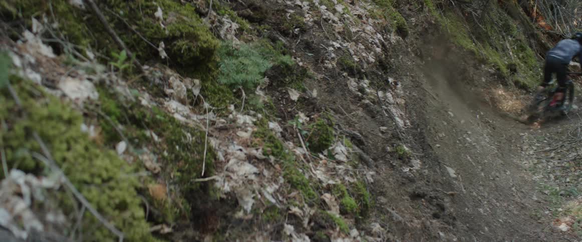 A person with a helmet slashes his rear bike tires through a dirt corner on a trail