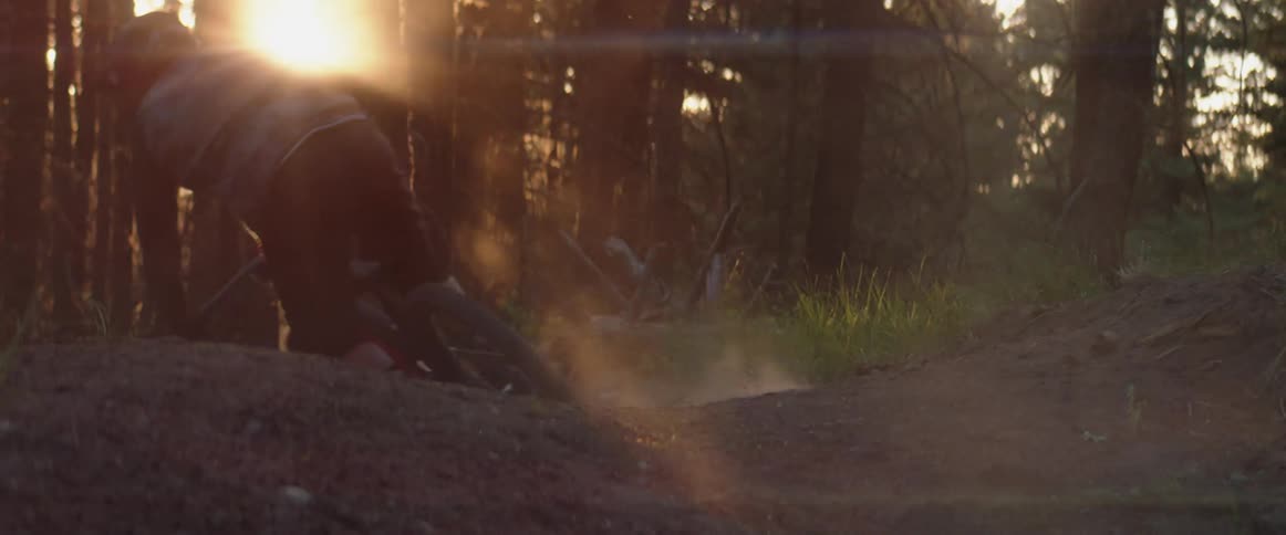 A person mountain bikes through dusty corners at sunset