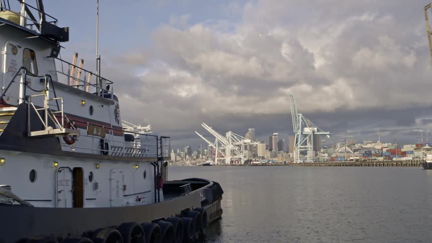 Pushing past tugboats and port equipment toward downtown Seattle in the distance
