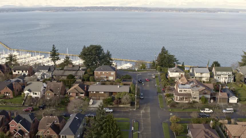 Tilt up reveal from the Sunset Hill and Ballard neighborhood to Shilshole Bay Marina and Puget Sound with the Olympic Mountains in the distance