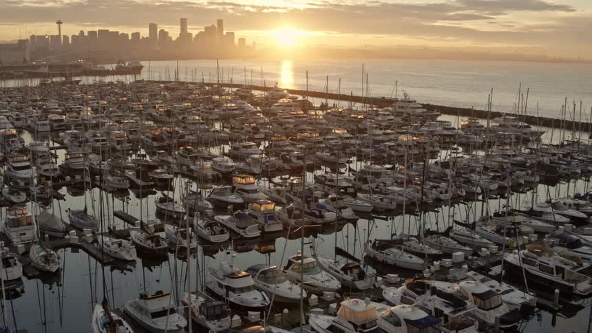 Tilt up reveal of the Seattle skyline at sunrise from over hundreds of boats docked at Elliott Bay Marina