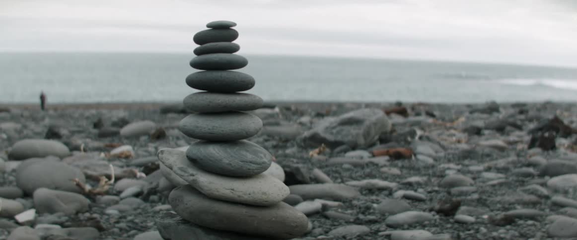 Rocks piled on the shore with people in the distance