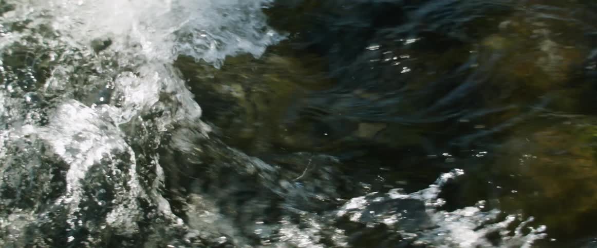 A swiftly flowing river splashes and twists around rocks to form rapids