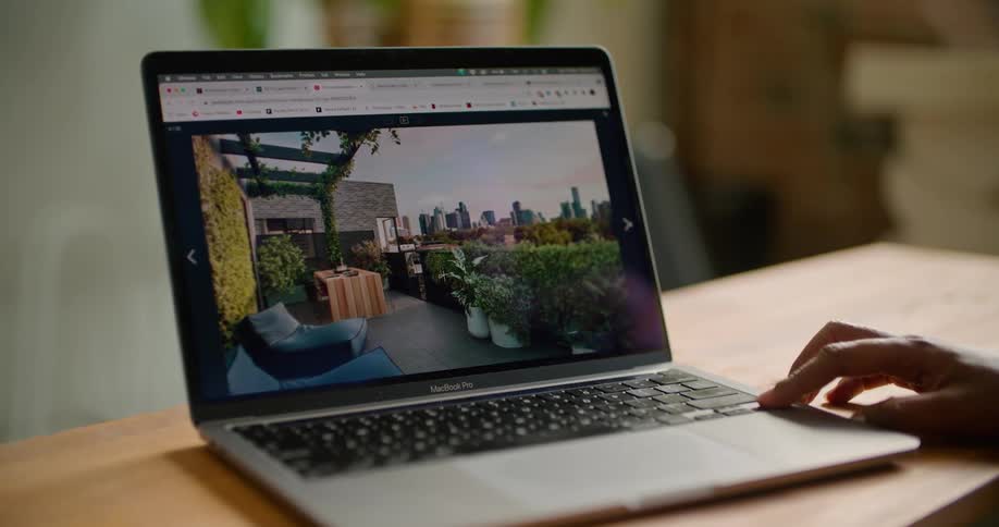 A finger taps an arrow key on a laptop changing the design photo on display