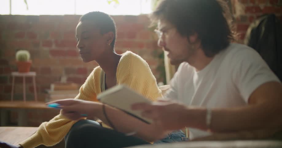 A man and woman sit at home on the couch and talk