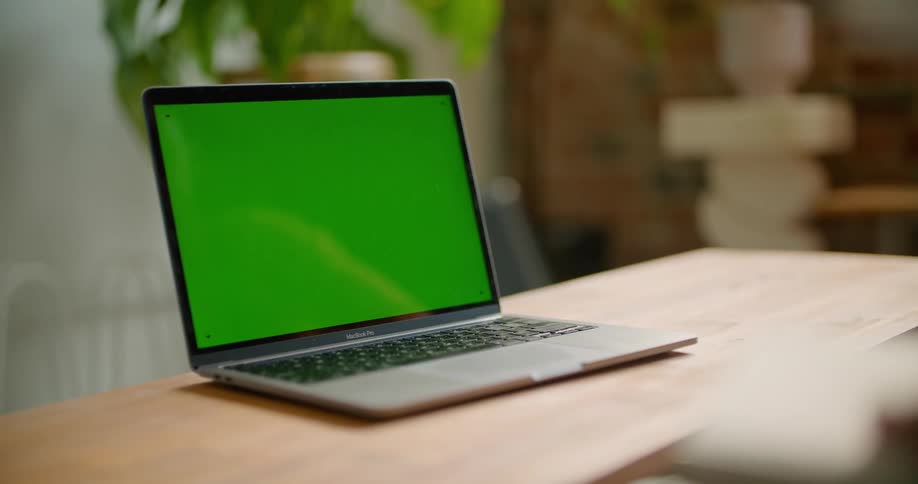 A womans hand points at the screen of a laptop on a coffee table