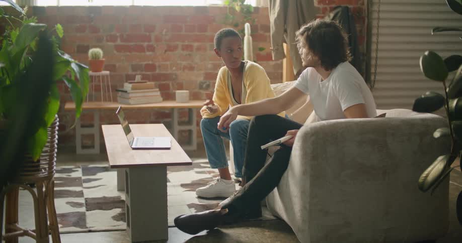 A man and woman sit on a couch in a home and talk
