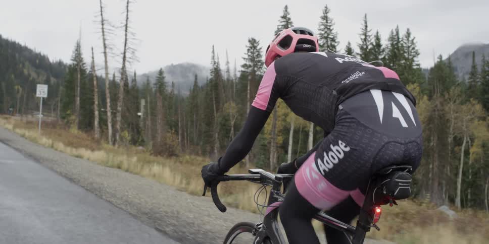Cyclist pedaling up a narrow grade wearing some pink gear
