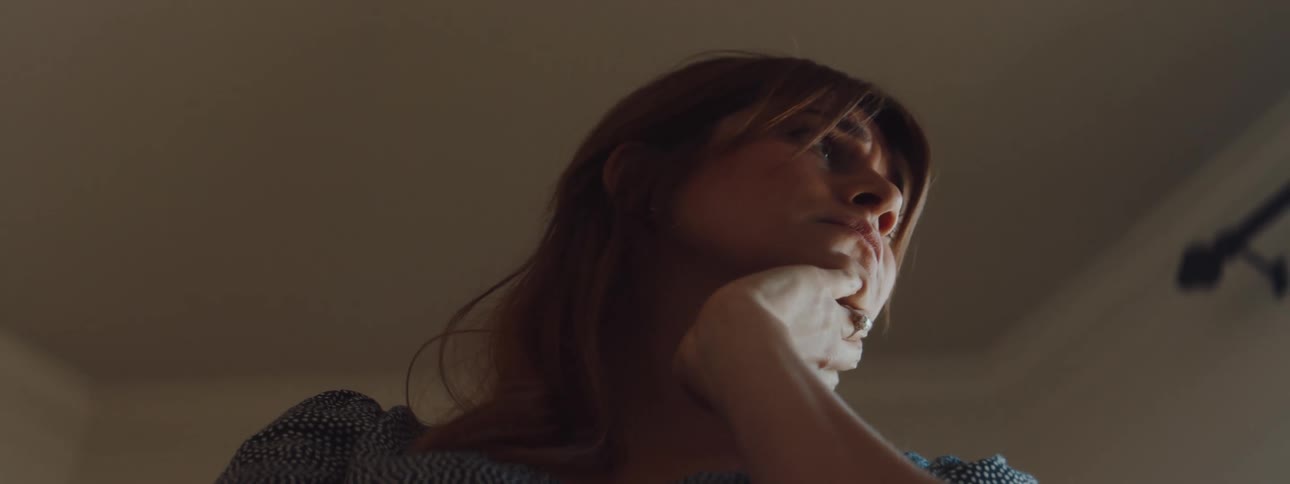 A distressed woman shakes and holds her head while indoors during the day