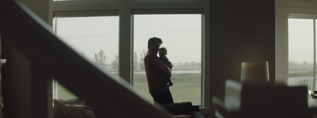 Father holding baby is silhouetted in the living room at home
