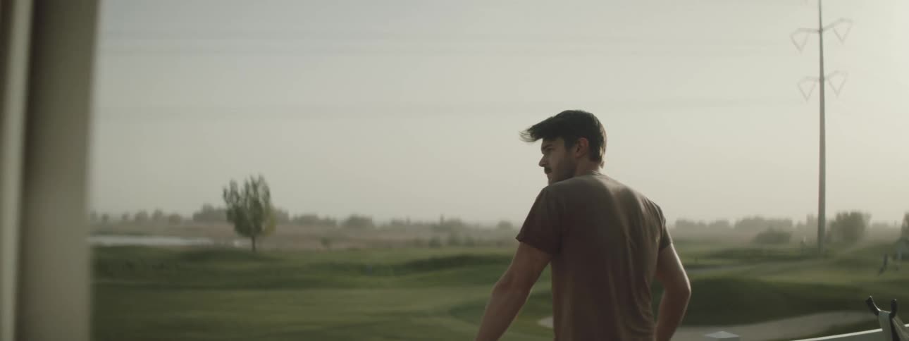 A man stands on his patio on a windy day and looks across the field