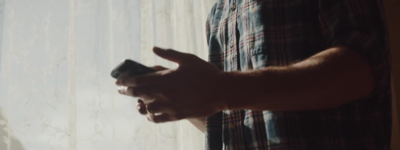 A man answers his phone by the window