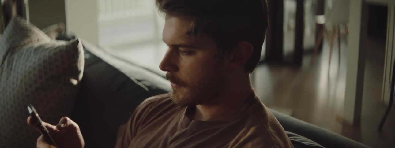 Man sitting in the couch texting on the phone